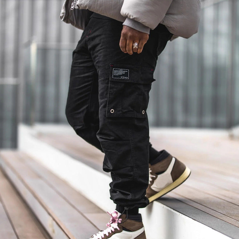 Pantalones cargo holgados de color liso con múltiples bolsillos y puños con cordón ajustable.